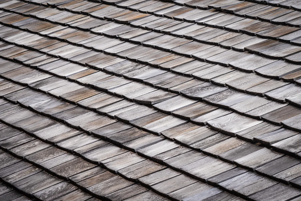 Close-up of weathered wooden roof shingles arranged in diagonal rows with gray-brown tones